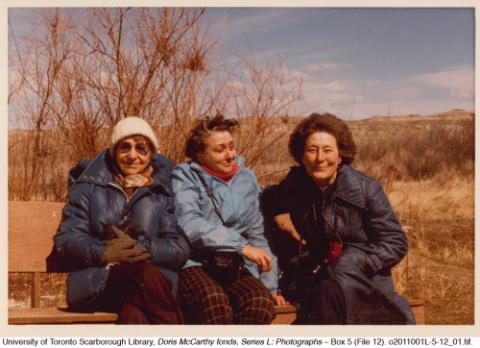 Doris, Barbara, and Nan seated on bench, in colour