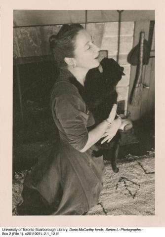 McCarthy woman holding black cat in front of fireplace