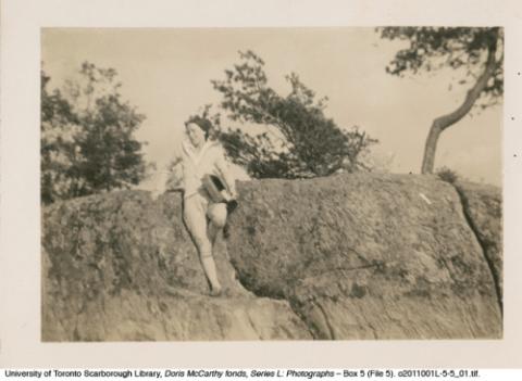 Woman leaning against rock with trees