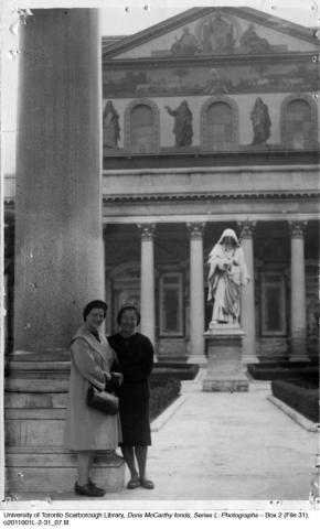 Doris and a friend in portico with hooded statue